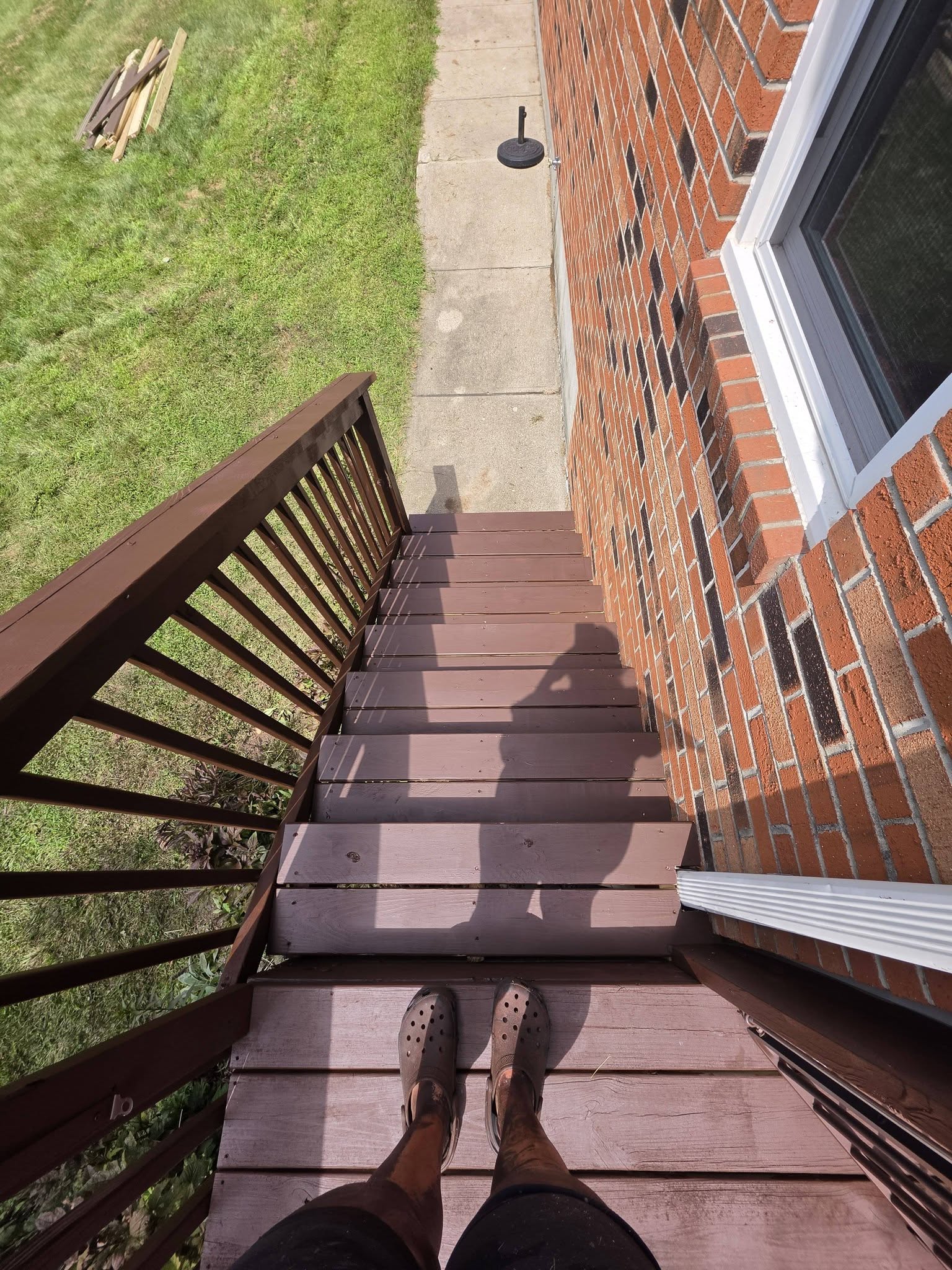 Restored brown-stained wood deck stairs beside a brick home